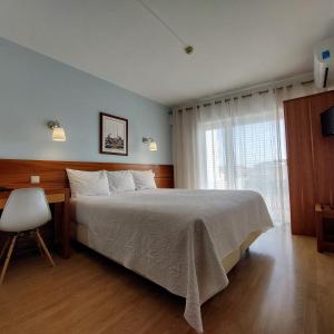 a bedroom with a bed and a desk and a window at Hotel Santiago in Ílhavo
