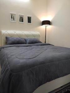 een slaapkamer met een bed met een blauwe deken en een lamp bij WAFID HOMESTAY 2 SERI ISKANDAR in Seri Iskandar