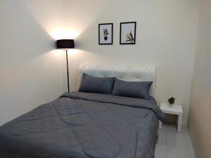1 dormitorio con 1 cama con edredón azul y lámpara en WAFID HOMESTAY 2 SERI ISKANDAR en Seri Iskandar