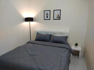 a bedroom with a bed with a blue comforter and a lamp at WAFID HOMESTAY 2 SERI ISKANDAR in Seri Iskandar