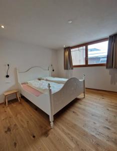 a white bed in a room with a wooden floor at Chasa Siringia in Samnaun