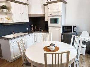 - une cuisine avec une table et des chaises blanches dans l'établissement Le 1A, Charmant Appartement au Cœur de la Ville, à Gérardmer