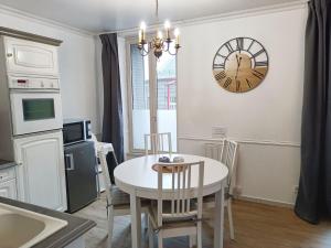une cuisine avec une table et une horloge au mur dans l'établissement Le 1A, Charmant Appartement au Cœur de la Ville, à Gérardmer