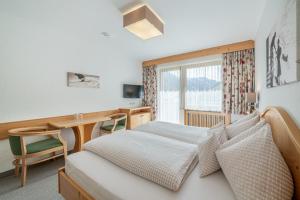 a bedroom with a bed and a desk and a window at Pension Bergfrieden in Obergurgl