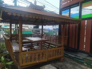 um gazebo de madeira com uma mesa e banco de madeira em โรงแรมพรถวิล ศรีสะเกษ Sisaket PonTaWin Budget Inn em Si Sa Ket