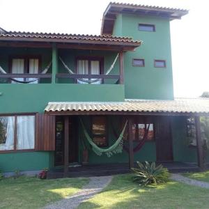 un edificio blu e verde con un'amaca di fronte di Green house a Praia do Rosa