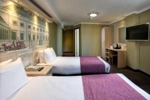 um quarto de hotel com duas camas e uma televisão de ecrã plano em President Hotel em Londres