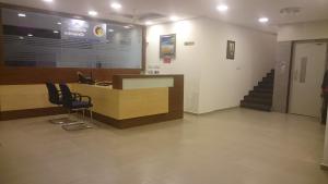 a lobby with a desk with chairs and a staircase at SAP Golden Grande Electronic City in Bengaluru