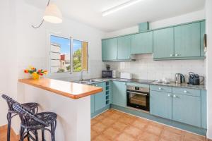 a kitchen with blue cabinets and a counter and chairs at Villa Libra in Cala en Forcat