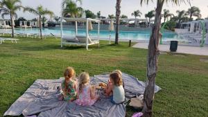 tres chicas sentadas en una manta junto a una piscina en Wellness Spa Hotel Principe Fitalia, en Siracusa