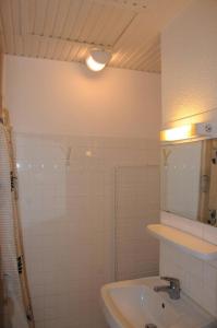 a white bathroom with a sink and a mirror at Arbousiers in Morcenx