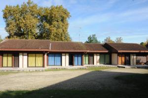 an old house with colorful doors and trees at Arbousiers in Morcenx