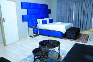 een blauwe slaapkamer met een bed en een stoel bij La Maison Guesthouse in Thohoyandou