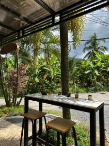 einen Tisch und zwei Hocker unter einer Pergola in der Unterkunft Baan Rosa Bangtao Beach in Strand Bang Tao