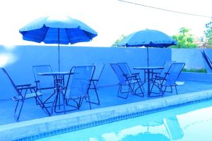 a group of chairs and tables with umbrellas next to a pool at La Maison Guesthouse in Thohoyandou