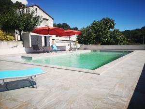 una piscina con agua verde y sombrillas rojas en E Cabane, en Rottani