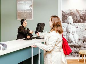 盧森堡的住宿－盧森堡中心火車站宜必思尚品酒店，站在柜台与顾客交谈的女人