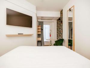 a bedroom with a white bed with a flat screen tv at ibis Styles Luxembourg Centre Gare in Luxembourg