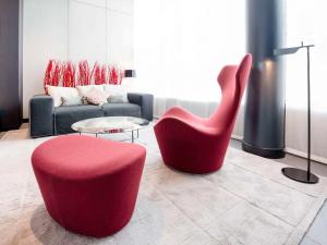 - un salon avec une chaise rouge et un canapé dans l'établissement Novotel Suites Genève Aéroport, à Genève