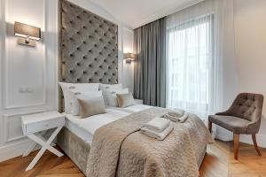 a bedroom with a large bed and a chair at Brabank Riverside - Sauna, Business & Gym by Downtown Apartments in Gdańsk