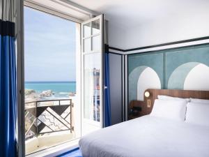 Mercure Plaza Biarritz Centre في بياريتز: غرفة نوم مع سرير وإطلالة على المحيط