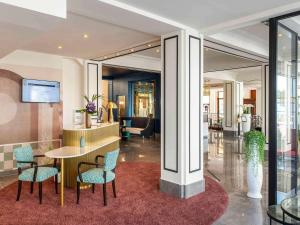 un hall avec une table et des chaises dans un bâtiment dans l'établissement Mercure Plaza Biarritz Centre, à Biarritz