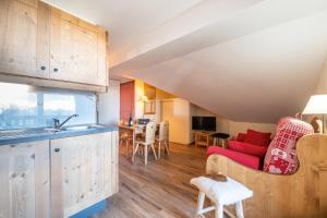eine Küche und ein Wohnzimmer mit einem roten Sofa in der Unterkunft L'Ours des Alpages - 301C - Piscine partagée in Villarembert