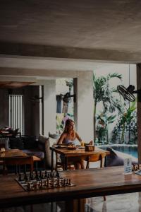 a woman sitting at a table in a living room at Surf Motel in Canggu