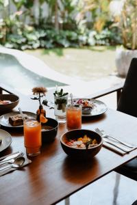 een houten tafel met borden eten en drinken bij Surf Motel in Canggu