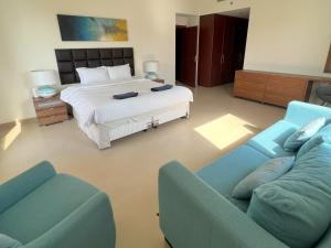um quarto com uma cama e dois sofás azuis em CozyNest - 3br Beachfront apt, JBR em Dubai