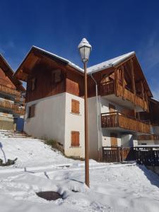 un edificio con una luz de la calle en la nieve en Appart - Chalet du Hameau des Aiguilles, en Albiez-Montrond