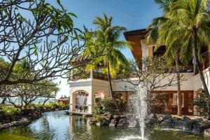 uma fonte no meio de um lago em frente a um edifício em Hilton Mauritius Resort & Spa em Flic-en-Flac