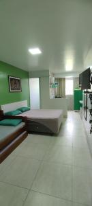 a bedroom with two beds and a green wall at Guest House Renascer K&W in Cabo Frio