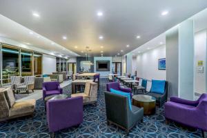 a waiting room with purple chairs and tables at La Quinta by Wyndham Houston Cypress in Cypress