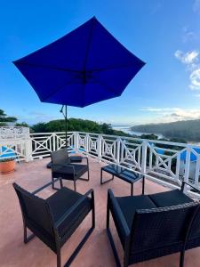 a patio with three chairs and a blue umbrella at Caribbean Estates Montego Bay 38 in Port Edward