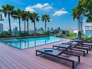 a swimming pool with lounge chairs and palm trees at ibis PJCC Petaling Jaya in Petaling Jaya
