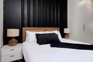 1 dormitorio con 1 cama con sábanas blancas y 2 lámparas en Sunrise Rivonia One Bed en Johannesburgo