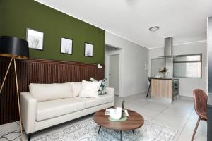 sala de estar con sofá blanco y pared verde en Sunrise Rivonia One Bed en Johannesburgo