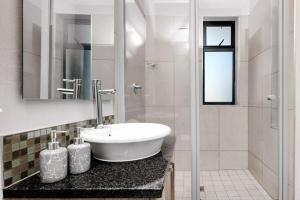 a white bathroom with a sink and a shower at Sunrise Rivonia One Bed in Johannesburg