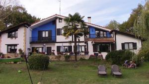 una casa blanca y azul con sillas delante en Agroturismo Atxarmin, en Elosu