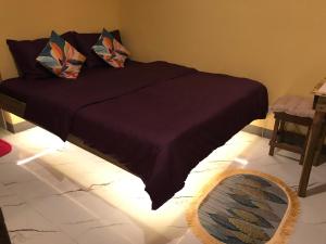 a bed with a dark purple blanket and pillows on it at Elmo’s place in El Nido