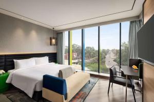 a bedroom with a bed and a desk and a window at Ramada Encore by Wyndham Bareilly Civil Lines in Bareilly +74 photos