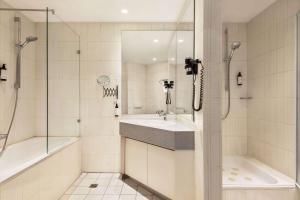 a white bathroom with a sink and a shower at Vienna House Easy by Wyndham Castrop-Rauxel in Castrop-Rauxel