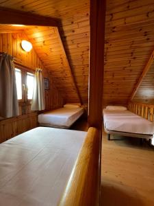 1 dormitorio con 2 camas en una cabaña de madera en Camping Playa Las Dunas, en El Puerto de Santa María