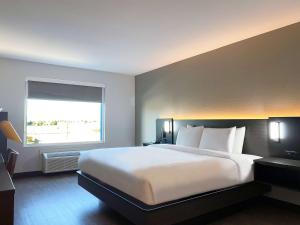 a bedroom with a large white bed and a window at Hawthorn Extended Stay by Wyndham Hobbs in Hobbs