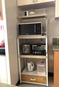 a microwave on a shelf in a kitchen at 1BR Suite in Manhattan Heights Tower D in Manila
