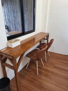 een houten bureau met 2 stoelen en een raam bij Basilia Guest House in Bantayan