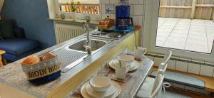 una cucina con lavandino e tavolo con stoviglie di Nordsee Ferienwohnung Nord a Dornumersiel