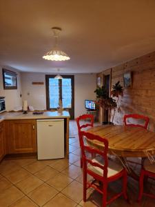 uma cozinha com uma mesa de madeira e cadeiras vermelhas em Pierre de Famille em Manigod
