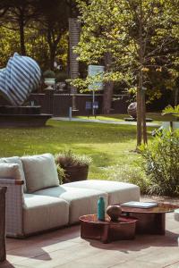 un divano su un patio in un parco di Villa Regina - MarePineta Resort a Milano Marittima